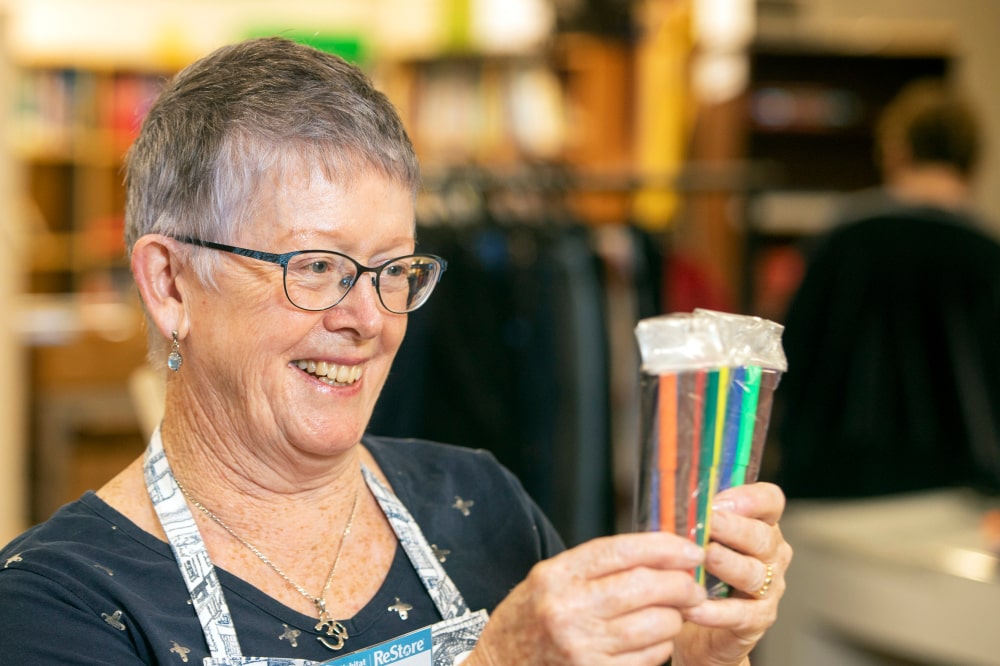 A lady at the store smiling at the coloured markers