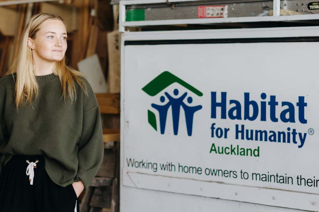 Taylor standing by the habitat for humanity sign