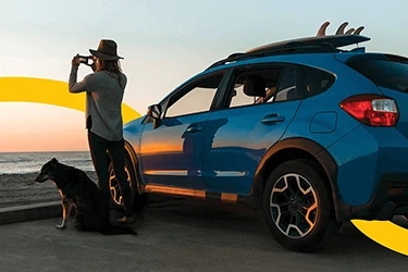 Person and Dog Standing by Car at Sunrise