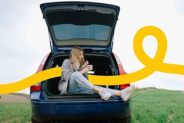 Woman Sitting in Open Boot of Car